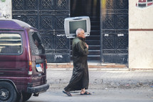 man carrying a tv on the streets of Egypt 