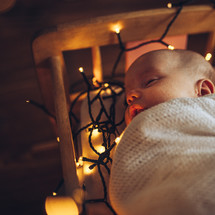 baby surrounded by Christmas lights 