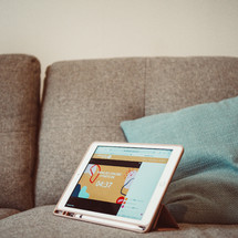 tablet opened to an online worship service sitting on a couch 