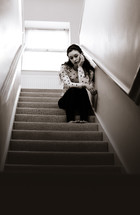 a sad teen girl sitting in a stairway 