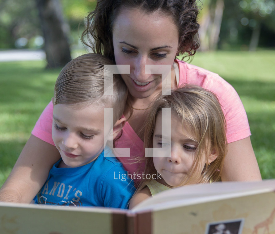 a mother reading to her children outdoors 