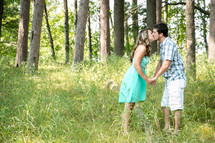 a couple kissing in a forest 