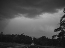 car on a road under cloudy sky 