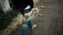 a teen girl carrying a skateboard 