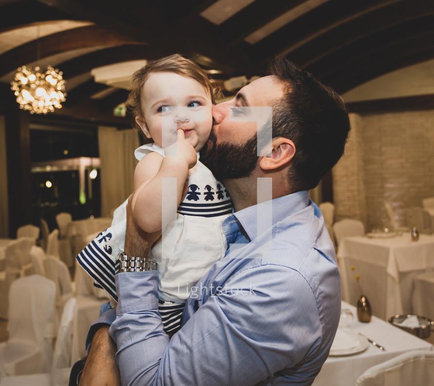 Young happy dad kissing daughter on cheek
