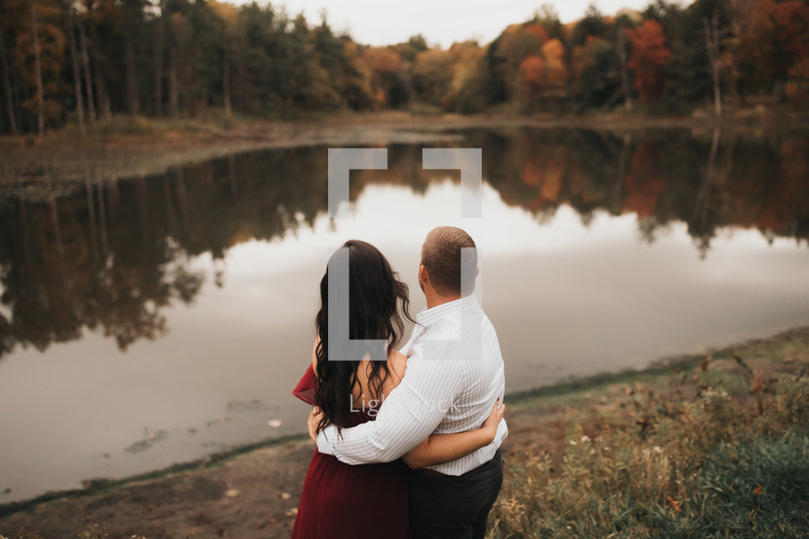 a couple embracing in front of a pond 