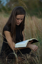 close up of woman reading a Bible in a field