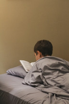 Boy in bed reading the Bible