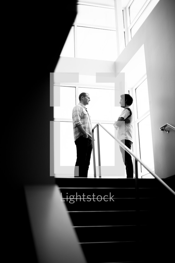 man and woman standing at the top of steps talking 