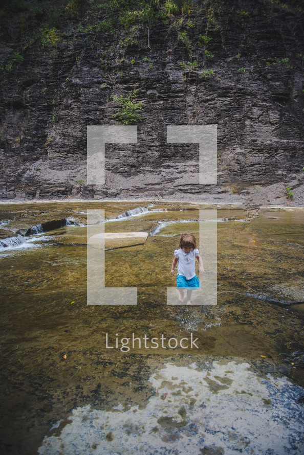 toddler walking in a stream bed 