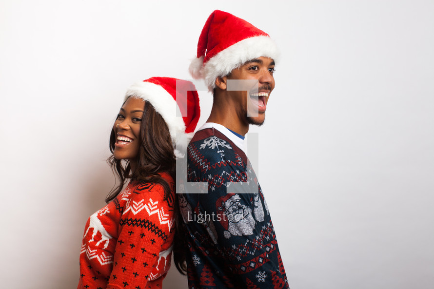 couple in ugly Christmas sweaters and santa hats