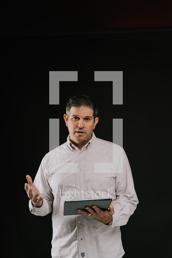 man holding a tablet speaking 