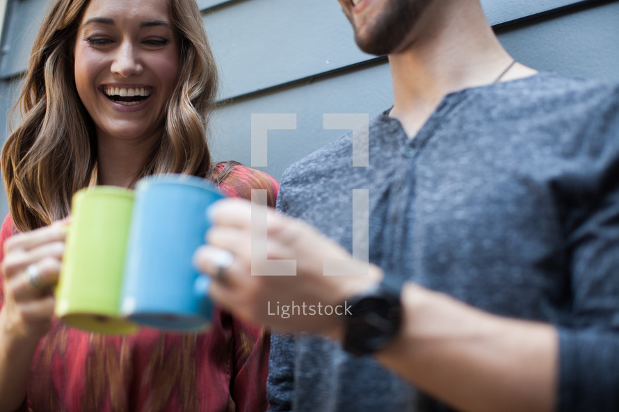 A smiling man and woman  toasting with coffee cups.