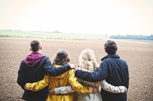 teens standing in a field together 