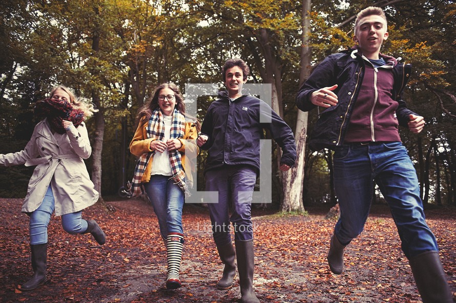 teens running through fall leaves outdoors 