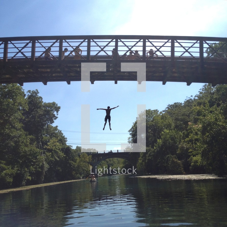 Man jumping from bridge into river