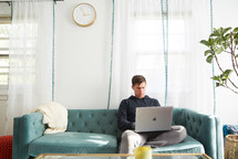 a man on a laptop sitting on a couch 