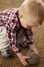 Little boy picking up a stone