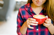 a woman in a plaid shirt holding a cup of coffee