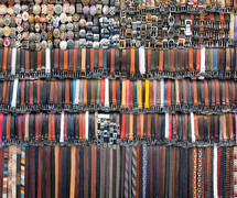 Many colored leather belts on a market.