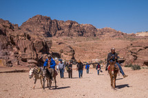 people riding on donkeys in a desert 