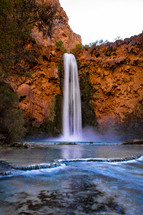 waterfall over red rock cliffs 
