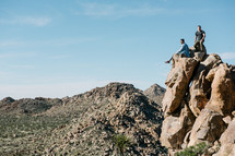 men sitting on a rock looking out at the desert 