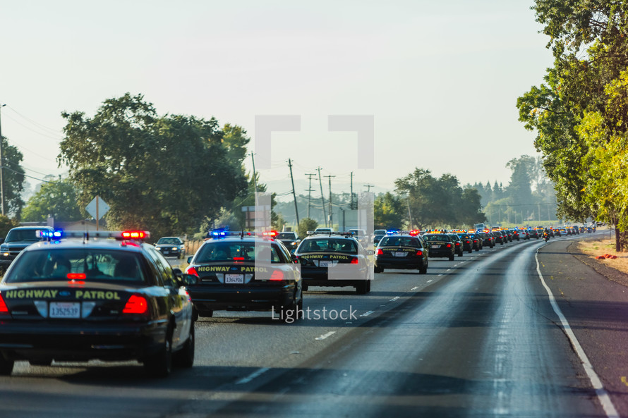 line of Highway patrol cars driving down freeway highway funeral procession  