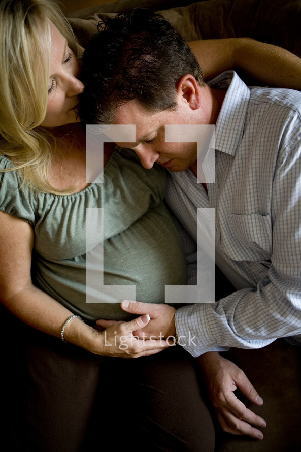 husband snuggling with his pregnant wife