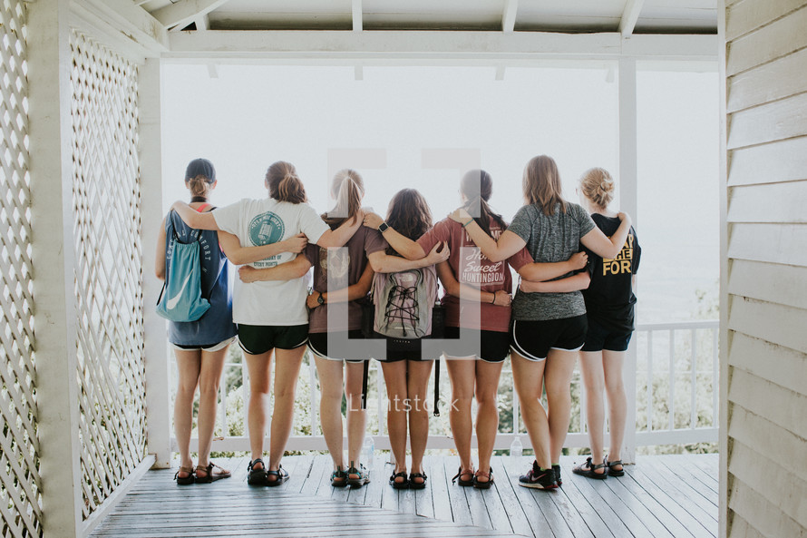 teen girls standing together with arms around each other on a porch 