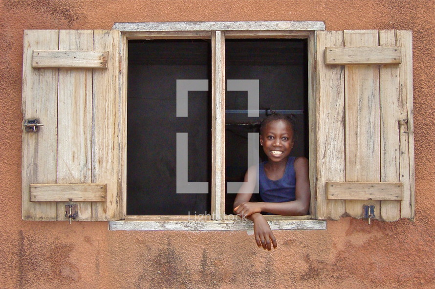 A little girl smiles from a window {Also try search for 'Ethnic Faces'} 