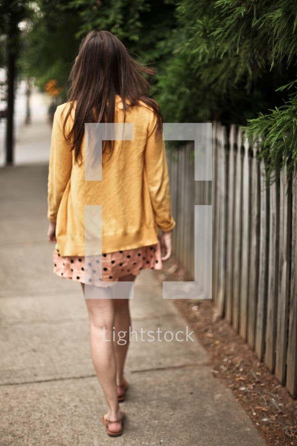 Woman walking down sidewalk