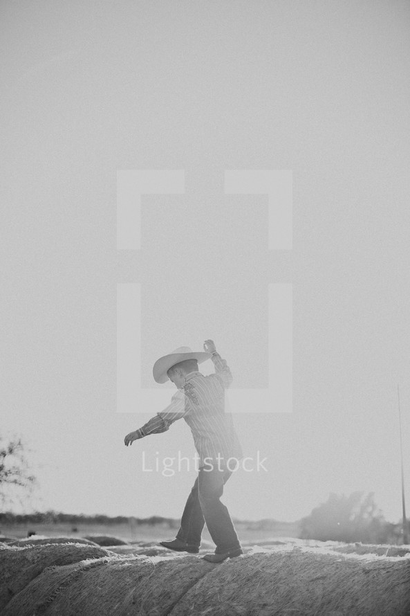 boy in a cowboy hat walking on hay bales