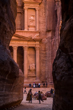 Petra: ancient temple carved into red rock with tourists 
