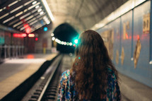 a woman standing on tracks in a tunnel 