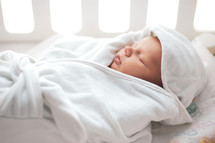 swaddled newborn in a crib 