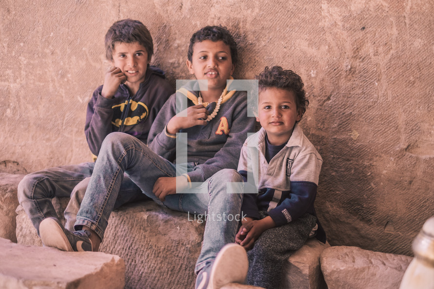 young boys sitting on rocks 