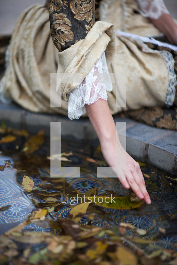 woman touching water in a fountain 