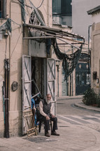 man sitting under a torn awning 