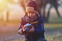 Creative child, kid photographer (a little boy) with a camera taking landscape