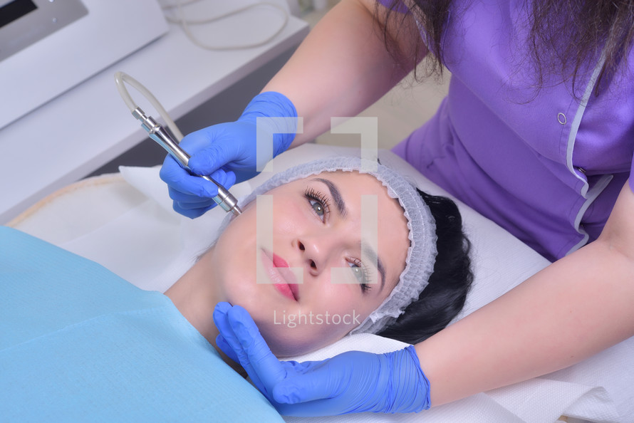 Young woman gets professional facial skin treatment in a professional beauty clinic