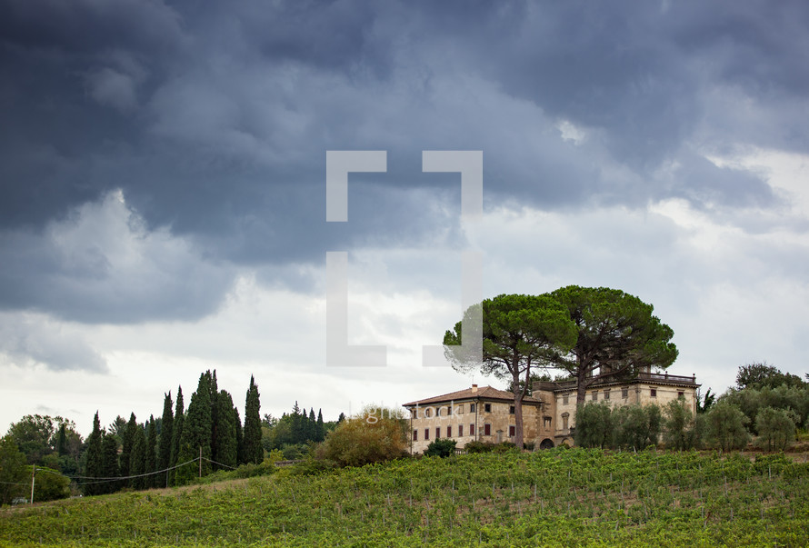 Tuscan hillside panorama with cloudy sky and typical local habitation.