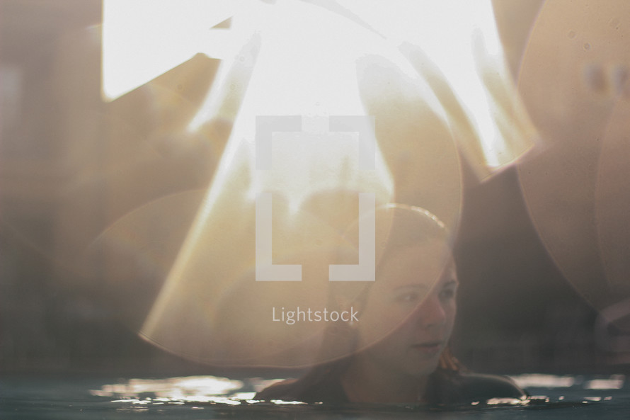 bright bokeh sunlight and a woman in a pool of water 