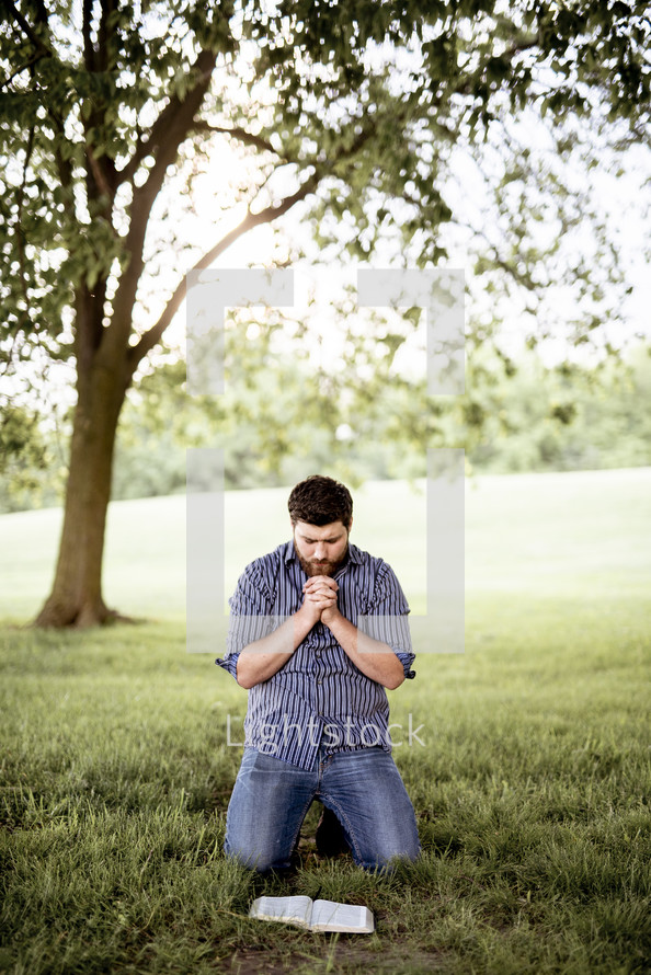 a man kneeling reading a Bible 
