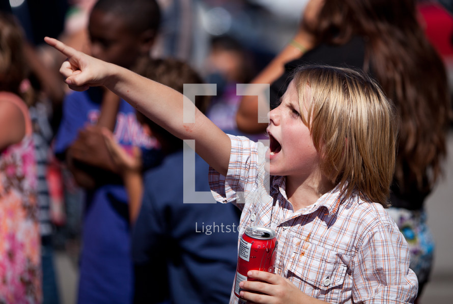 Child pointing and holding a drink
