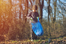  boy picks up spring forest at sunset. Environment plastic pollution