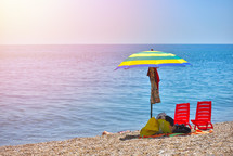 Pair of sun loungers and a beach umbrella on a deserted beach; perfect vacation concept