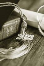 a 2023 graduation tassel on a bible with a cap