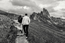 a couple walking on a path on a mountainside 