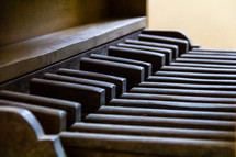 The wooden pedalboard of a vintage pipe organ in profile